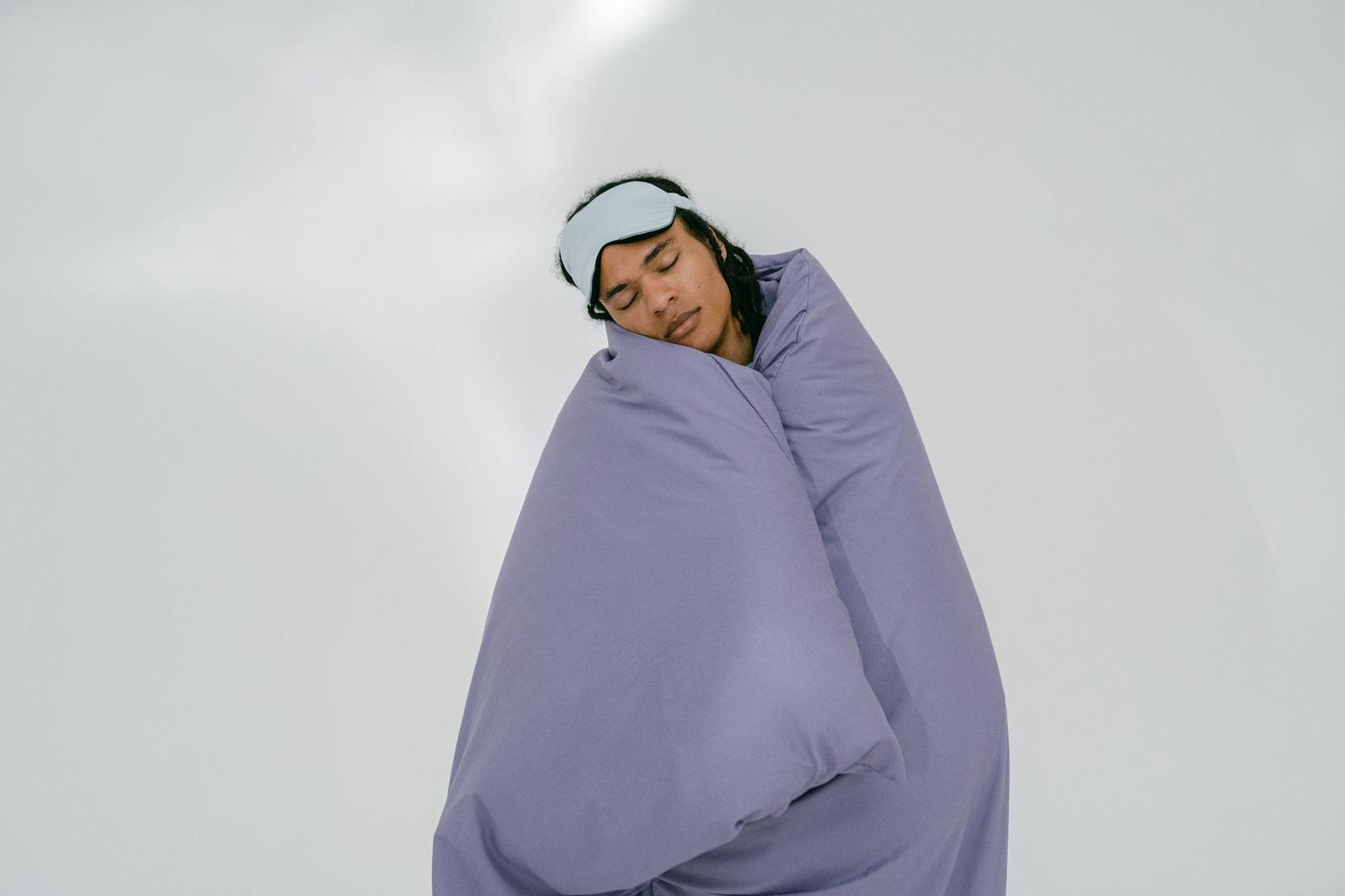 A Man Sleeping While Covering His Body with Purple Comforter